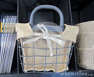 Metal basket with burlap liner on shelf. Stock Photo