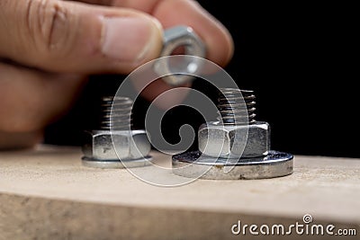 Metal bolts and nuts for joining wood. Tightening the screws with an adjustable wrench Stock Photo