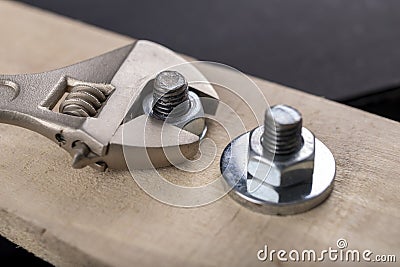 Metal bolts and nuts for joining wood. Tightening the screws with an adjustable wrench Stock Photo