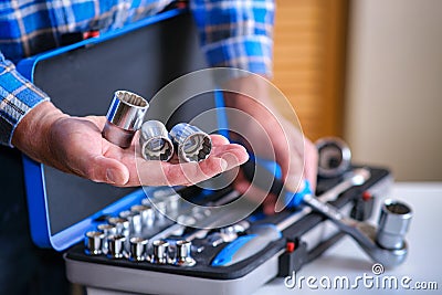 Metal box with a set of keys. A locksmith in a checked shirt holds a key attachment in his hand. Stock Photo