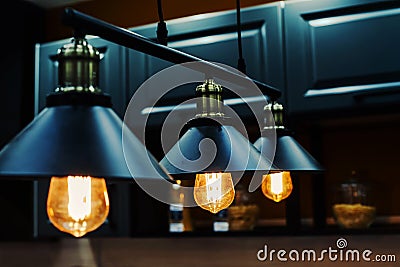 Metal chandeliers in retro style on the background of the kitchen set. Dark room with brightly lit lamps Stock Photo