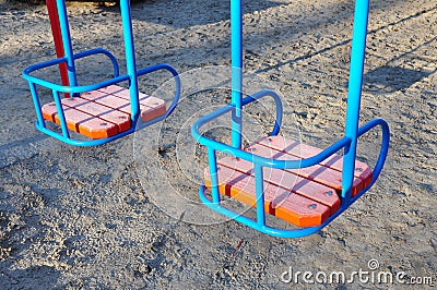 Metal colorful swings with wooden seat on children playground Stock Photo