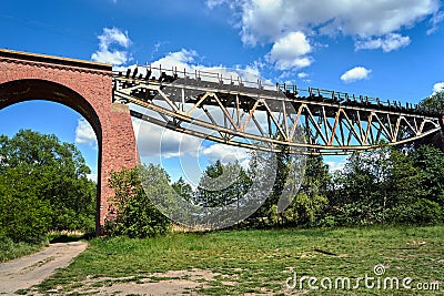 Metal construction of a destroyed railway viaduct against the sky Stock Photo