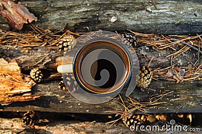 Metal cup with hot coffee on the wooden background with the coins, needles and bark of tree, top view. Stock Photo