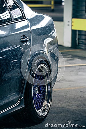 Wet silver shining car body and blue purple metal wheels parked in a parking garage Stock Photo