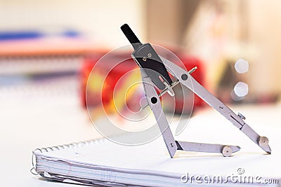 A metal drawing - drafting compass on a notebook. Stock Photo