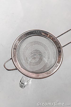 Metal drink strainer on glass cup on white table Stock Photo