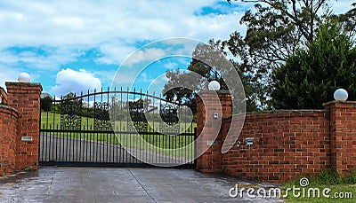 Metal driveway entrance gate set in brick fence Stock Photo