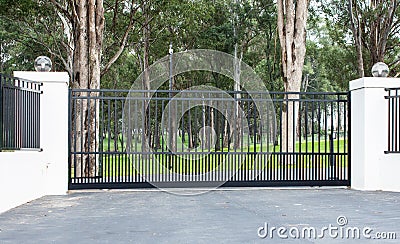 Metal driveway rural property entrance gates set in brick fence with lights and eucalyptus gum trees in background Stock Photo