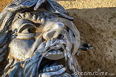 Metal face sculpture in the sand by the ocean Editorial Stock Photo