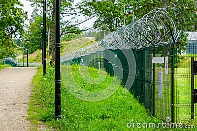 A metal fence of a military object with barbed wire Stock Photo