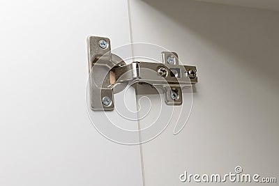 Metal furniture hinge mounted on the door of cabinet Stock Photo