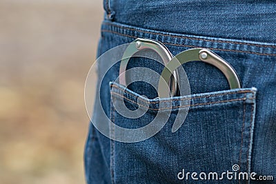 Metal handcuffs in back jeans pocket Stock Photo