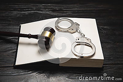 Metal handcuffs, book and judge gavel on the table Stock Photo