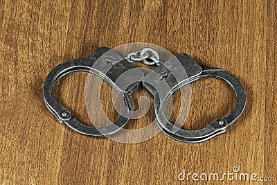 Metal handcuffs lie on the wooden surface Stock Photo