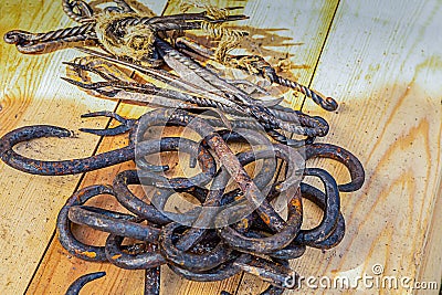 Metal hook a double-edged butcher tool lies a pile on a wooden table Stock Photo