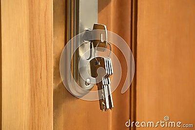 Metal key from the bunch of keys inserted into the lock of the wooden door. Warm colors, close up Stock Photo