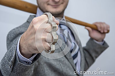 Metal knuckles in a man`s hand, a wooden bat behind his back, a prohibited weapon in a fight, a heavy blow, street thugs, urban Stock Photo