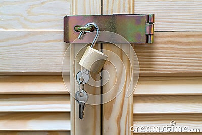 Metal lock with keys hanging on modern wooden cabinet with strips in classic rustic style. Locker wardrobe closet with shutter Stock Photo