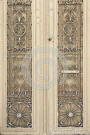 Metal old beige double winged heavy big aged door with wrought iron ornaments Stock Photo