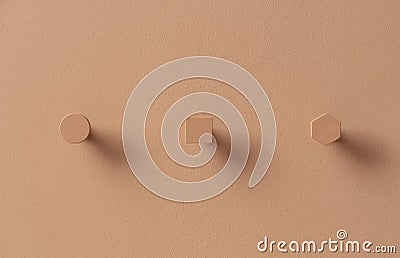 Metal orange hangers in forms of circle and square and hexagon on colorful wall in studio Stock Photo