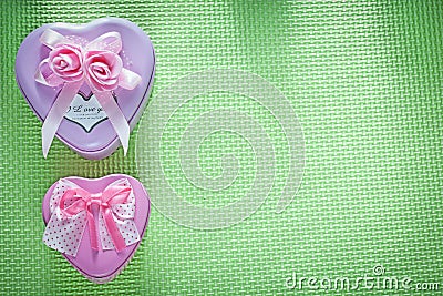 Metal pink heart-shaped present boxes on green surface holidays Stock Photo