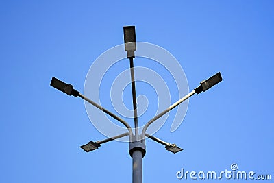 Metal pole with five modern LED lights set against clear blue sky. Street lighting. Bottom view. Stock Photo