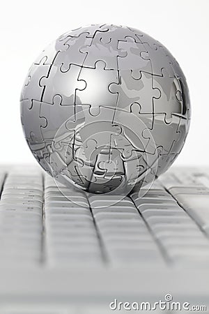 Metal puzzle globe on computer keyboard Stock Photo