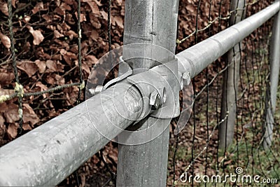 Metal scaffold pipe fencing with screws and hedge in background Stock Photo