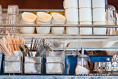 Metal shelves with coffee utensils dishware, sugar pot, and glasses Stock Photo