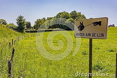 Metal sign with inscription: Honden aan de lijn, meaning: Keep your dog on a leash, entrance to nature reserve Stock Photo