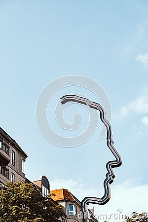 Metal sign resembling a human face from a side on a backdrop of a blue sky Editorial Stock Photo