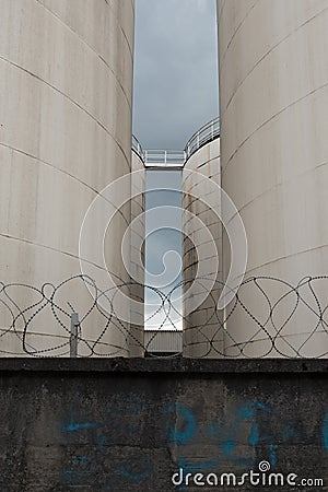 Metal silo, store behind a concrete wall with barbed wire Stock Photo