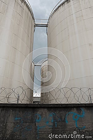 Metal silo, store behind a concrete wall with barbed wire Stock Photo