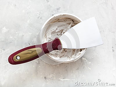 Metal spatula on container with putty Stock Photo