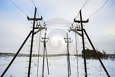 Metal supports of overhead power lines in the winter on field. Stock Photo