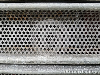 Metal surface with round holes and straight line borders above and below. Stock Photo