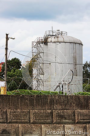 metal tower with flammable fuel in the territory of a fence with barbed wire Stock Photo