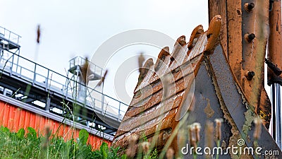 Metal tractor ladle among green grass against construction Stock Photo