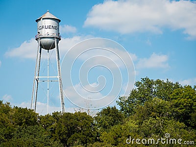 Metal water tank of small texas town Gruene standing high above trees on sunny day Stock Photo