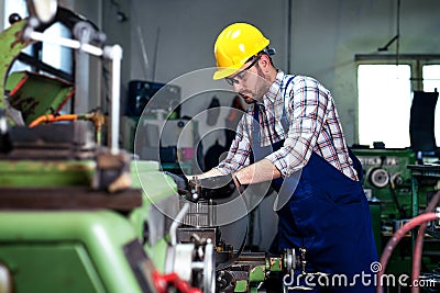 Metal worker turner operating lathe machine at industrial manufacturing factory. Stock Photo