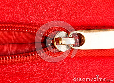 Metal zipper on intense red leather jacket or purse detail close up macro. The zipper is partly open and binding together Stock Photo
