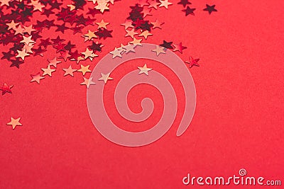 Metallic confetti on festive red paper background. Stock Photo