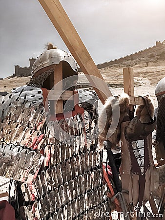 Metallic helmet, brilliant plate armor, sword against the background of ancient fortress wall, ancient Roman armor Stock Photo