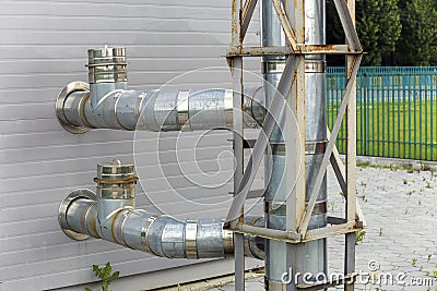 Metallic water supplying pipes installed on house exterior wall Stock Photo