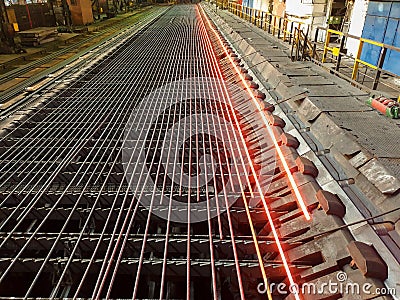 Metallurgical plant. Metal production process. The hot metal moves along rollers and cools down to take the finished shape. Stock Photo