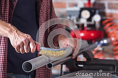 Metalworker using a hand metal brush Stock Photo