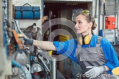 Metalworker woman in workshop grabbing tool Stock Photo