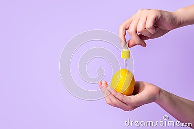 Metaphor, bottle serum with vitamin C for skin in lemon in female hand. The concept vegetable cosmetics and aromatherapy Stock Photo