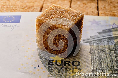 A metaphor for the cost of sweetness, as a Euro banknote covers a pile of brown sugar Stock Photo